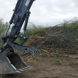 Grapple bucket stacking cleared brush and timber for disposal