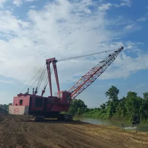 Dragline dragging the bucket through the channel with the spoil bank building alongside