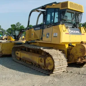 Winch-equipped crawler dozer staged on gravel with other equipment behind it