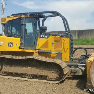 Crawler dozer between two excavators, with the floodwall and rail in the background