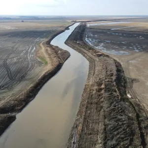 The finished channel — a cleaned-out reach curving between shaped banks and farmland