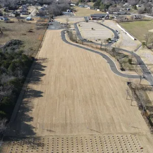 Aerial view of the graded expansion area with the new access roadway curving toward the completed burial sections