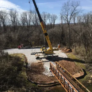 Aerial of the erection operation with the crane, delivery trailer and the first section landed on its abutment