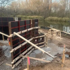 Abutment wall formwork braced and tied out, ready for concrete placement at the slough bank
