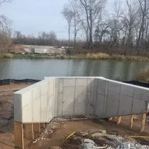 A completed abutment and its wing walls, with the opposing abutment visible across the slough