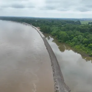 Aerial view of the armored embankment separating the main river from the landside water, with no equipment on site