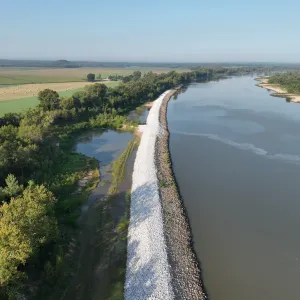 Aerial view of the completed riprap along the riverbank with hay fields and round bales on the landside